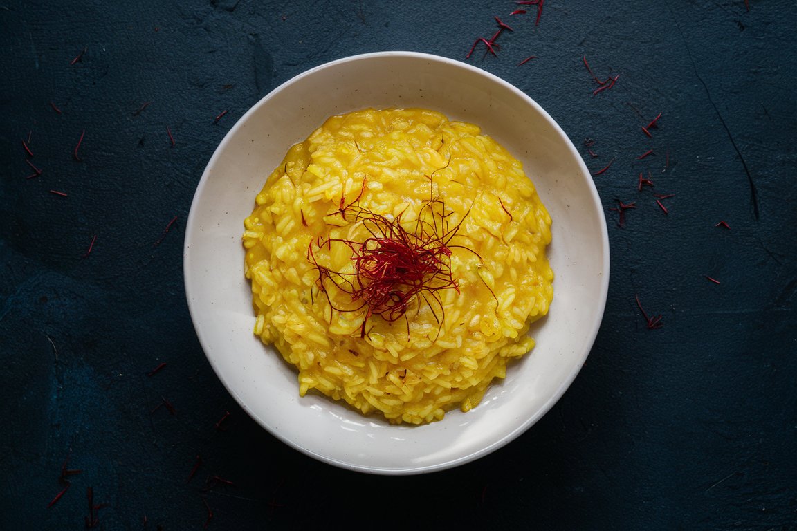 Cremiges Safranrisotto in einer weißen Schale – italienische Delikatesse mit goldenem Safran.